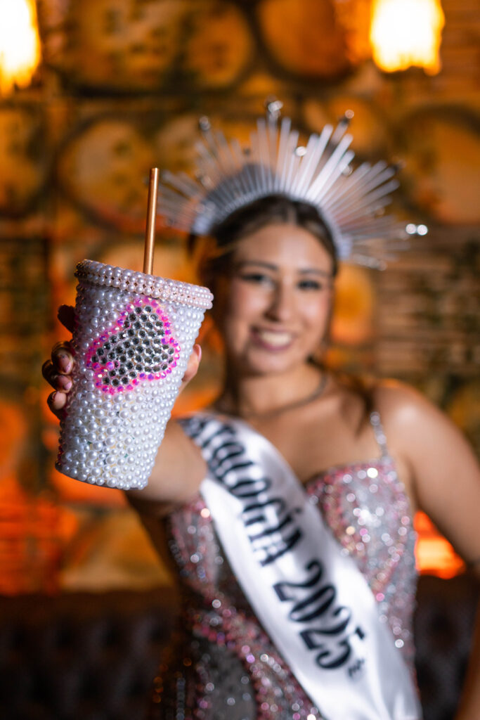 Egresada con banda y vaso decorado brindando en su recepción