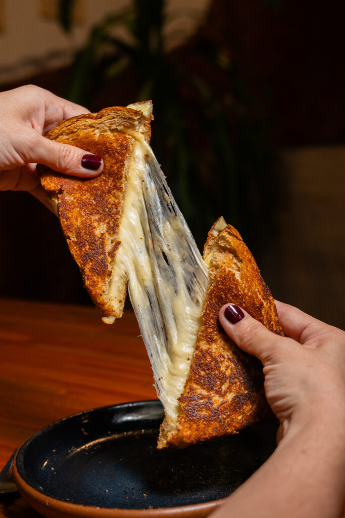 Tostado de queso fundido estirándose, fotografía gastronómica