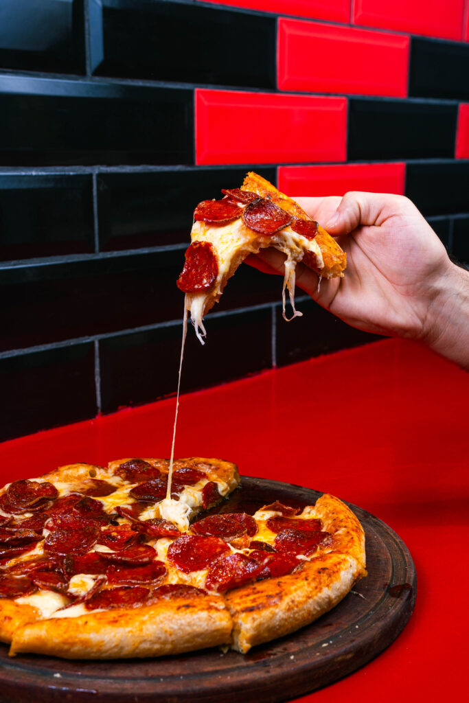 Porción de pizza de pepperoni con queso estirado, fotografía gastronómica